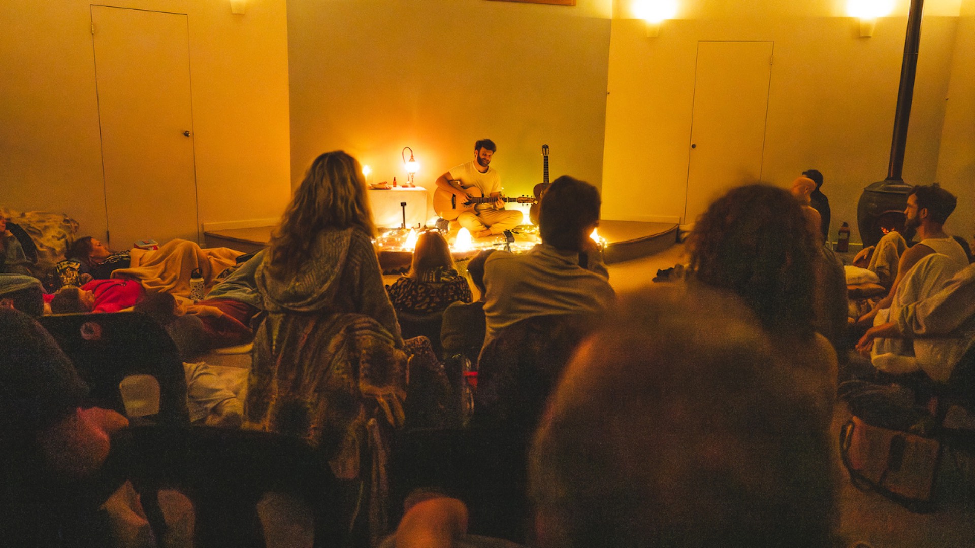 Nathan Maingard performing at a Songs for Joy gathering in Cape Town, a candlelit room full of people listening
